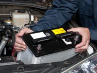 A car mechanic replaces a battery.